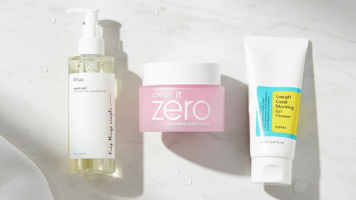 A marble countertop with Korean cleansing oils, balms, and gel cleansers arranged by skin type